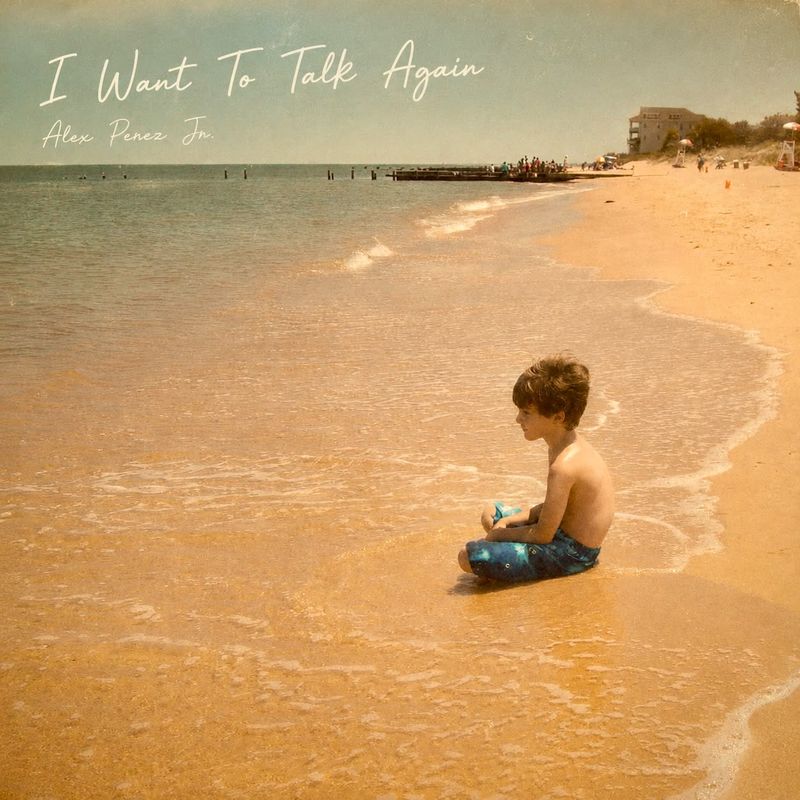 Cover art for “I Want To Talk Again” by Alex Perez Jr.: a young boy sitting at the water’s edge on a sunlit beach