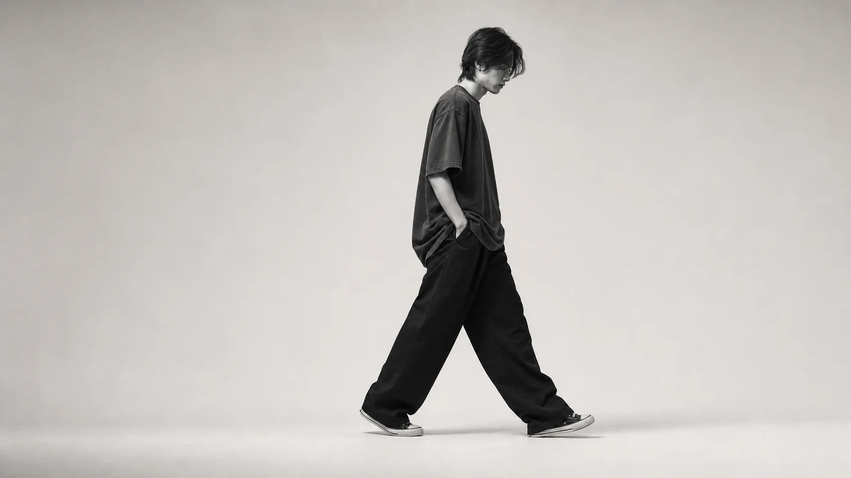 Model walking in an oversized charcoal APJ FAY streetwear look